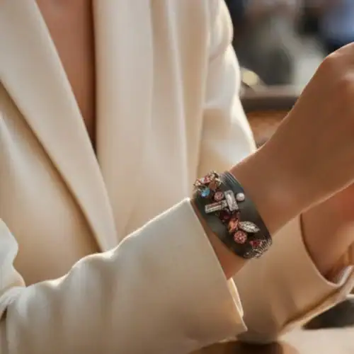 AryA Gioielli | Bracciale donna cuff rigido multifilo in ottone rodiato nero con strass - 0604BC - indossato da modella con gaicca bianca e braccia appoggiate su tavolo